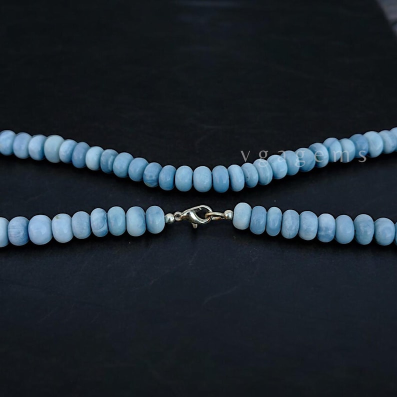 Op de afbeelding: Een lichtblauwe edelsteenketting met een zilveren sluiting. De ketting is gemaakt van ronde kralen en is ongeveer 45 centimeter lang.