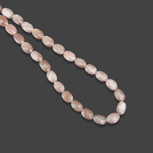 May include: A strand of oval-shaped, light pink sunstone beads. The beads have a faceted, slightly iridescent finish.