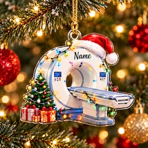 May include: A clear acrylic Christmas ornament shaped like a CT scanner machine, decorated with a Santa hat, colorful string lights, and a small Christmas tree with presents. The word Name is printed in black script on the top of the scanner.