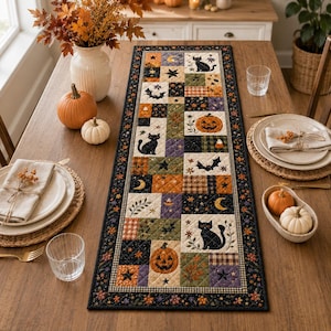 May include: A rectangular quilted table runner featuring a patchwork design with Halloween motifs including black cats, orange pumpkins, bats, stars, and crescent moons in a color palette of black, orange, purple, cream, and olive green.