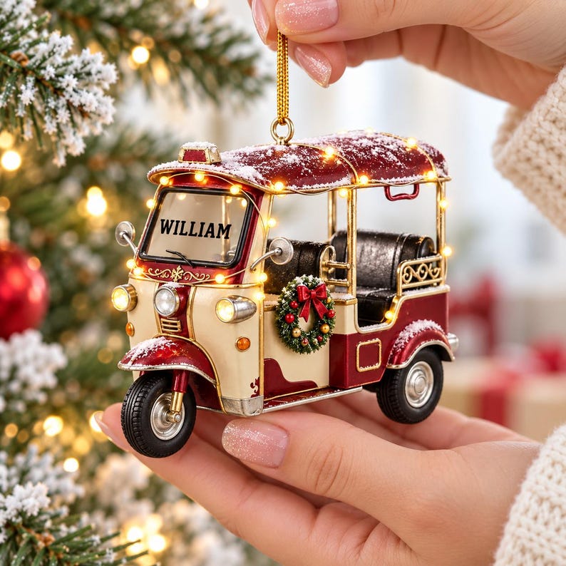 A person's hand holding a decorative ornament in the shape of a red and white vehicle, with the name "William" displayed on the front.