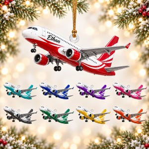 May include: A hanging airplane ornament featuring the name Ethan printed on the side. The plane is available in multiple colors including red, teal, blue, purple, pink, black, green, yellow, and orange, each with a gold hanging cord attached.