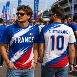 A man wearing a blue and red jersey with the word "FRANCE" on it, standing in front of a crowd of people.