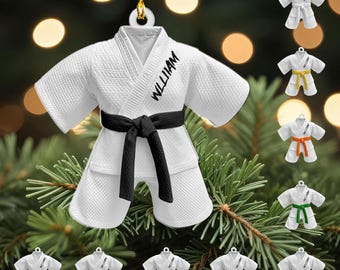 May include: White karate uniform ornament with a black belt and the name "WILLIAM" printed on the front. Additional ornaments with different colored belts are also shown, including yellow, orange, green, brown, red, purple, and blue.