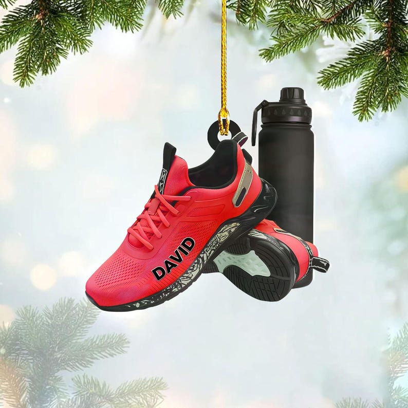 A pair of red running shoes with the name "DAVID" printed on them, hanging from a string.