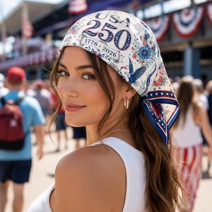 May include: A white bandana featuring a patriotic design with the text USA 250 and 1776-2026. The fabric is decorated with blue eagles, red and blue floral patterns, and small stars. The edges are finished with a dark blue border and white stars.