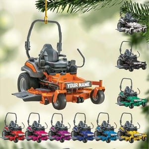 May include: Orange and gray lawn mower ornament with the text "YOUR NAME". The ornament is hanging from a gold string. Additional lawn mower ornaments in various colors are also shown.