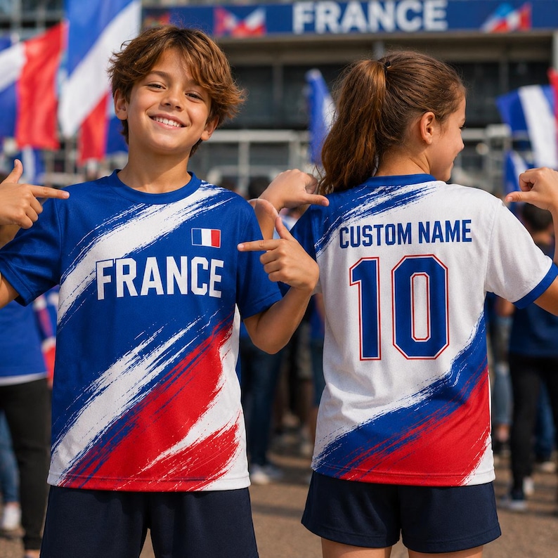 A young boy and girl wearing matching blue and red soccer jerseys with the word "France" on them, smiling and pointing at the camera.