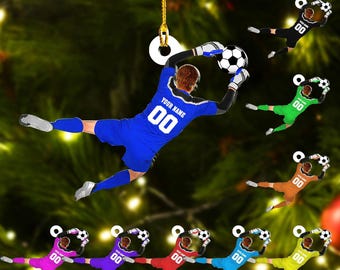 May include: A collection of soccer-themed ornaments in various colors, each depicting a player in action. The main ornament shows a blue-clad goalkeeper with the text "YOUR NAME" and the number "00". Other ornaments feature players in green, orange, black, purple, red, blue, and yellow.