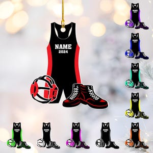 May include: Black and red wrestling-themed ornament. The ornament features a wrestling singlet with "NAME 2024" printed on it, a headgear, and wrestling shoes. Additional ornaments with different color schemes are also shown.