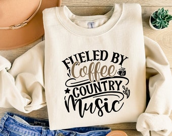 May include: A cream-colored sweatshirt with the text "Fueled by Coffee & Country Music" in black and brown lettering.