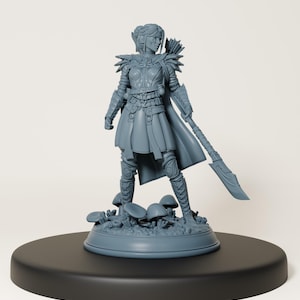 Puede incluir: Una figura miniatura pintada en gris de una guerrera elfa femenina con arco y flecha, de pie sobre una base cubierta de hongos. La figura está en una postura de combate, con su espada levantada.