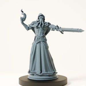 Peut inclure: Statue grise d'une figure vêtue d'une robe avec des tentacules, tenant un objet enflammé et une épée. La figurine est sur une base circulaire noire. La statue présente des détails complexes et une robe fluide. Environ 20 cm de hauteur.