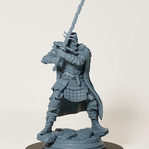 Op de afbeelding: Een grijze figuur van een krijger in volledige wapenrusting, die een groot zwaard omhoog houdt. Het beeld heeft gedetailleerde bepantsering en een vloeiende cape. Het staat op een rotsachtige basis bovenop een zwarte cirkelvormige standaard, met een middeleeuws of fantasiethema.
