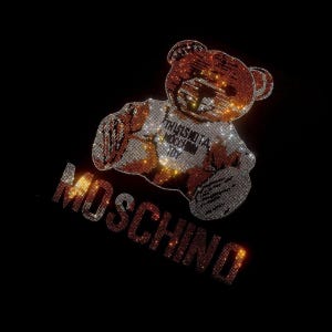 Peut inclure: Un t-shirt noir avec un ours en strass brun et blanc portant un t-shirt blanc avec le texte "This Is Not A Toy" en noir. Le mot "Moschino" est écrit en strass sous l'ours.