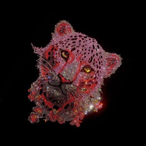 Könnte beinhalten: Ein funkelndes Design eines Leopardenkopfes in Rosa und Rot auf schwarzem Hintergrund. Das Design ist mit glitzernden Strasssteinen versehen, die einen schillernden Effekt erzeugen. Die Augen sind gelb, und das Design ist auffällig.