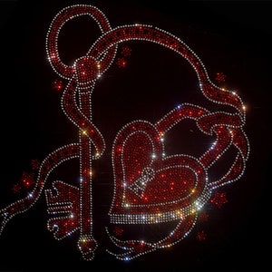 Op de afbeelding: Een rood strass hart met een sleutelgat en een rode strass sleutel bevestigd aan een rood lint. Het ontwerp is op een zwarte achtergrond.