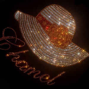 Puede incluir: Un fondo negro con un diseño de sombrero en strass dorado y plateado y la palabra "Chanel".