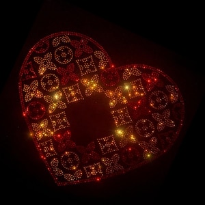 Op de afbeelding: Een hartvormig ontwerp gemaakt van rode en gouden strass steentjes. De strass steentjes zijn gerangschikt in een patroon van vierkanten en cirkels.