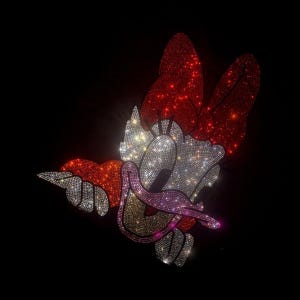 May include: A cartoon character with a red bow, white eyes, and a pink tongue, made entirely of rhinestones. The character is set against a black background.