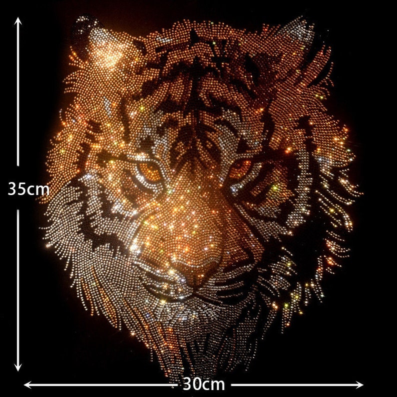 Op de afbeelding: Een close-up van een tijgergezicht gemaakt van strass. Het tijgergezicht is 30 cm breed en 35 cm hoog. De strass zijn goud, zilver en helder.