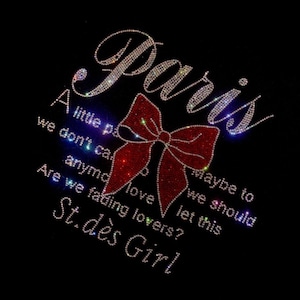 May include: A black t-shirt with a rhinestone design that says "Paris" with a red bow and the text "A little part of me we don't care anymore love let this maybe to we should are we fading lovers? St.dès Girl"