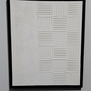 May include: White framed wall art with a raised, textured design. The left side features a series of overlapping semi-circles, while the right side features a grid of squares with vertical lines.