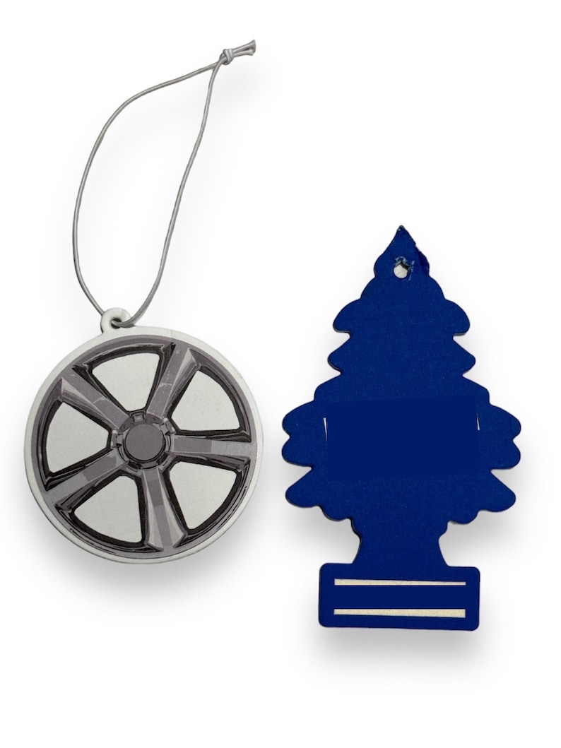 May include: Two car air fresheners, one shaped like a car wheel and the other shaped like a Christmas tree. The wheel is silver and gray, and the tree is blue.