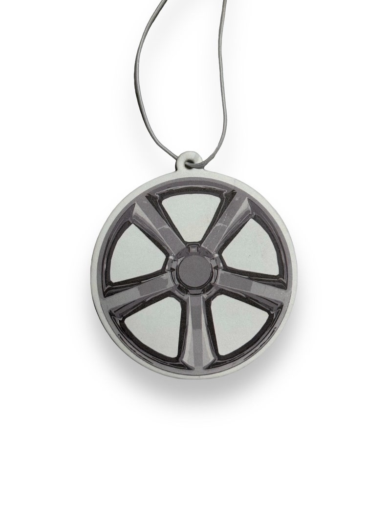 May include: A round car air freshener with a silver and black design of a car wheel with five spokes.