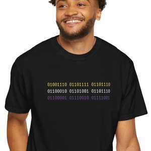 Nonbinary Agender person showing subtle pride by wearing techwear inspired nonbinary Comfort Colors t shirt in black with non-binary flag color text that reads in binary code, "nonbinary".