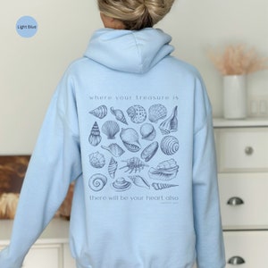 Puede incluir: Sudadera con capucha azul claro con un gr&aacute;fico de conchas marinas y el texto "where your treasure is there will be your heart also Matthew 6:21"