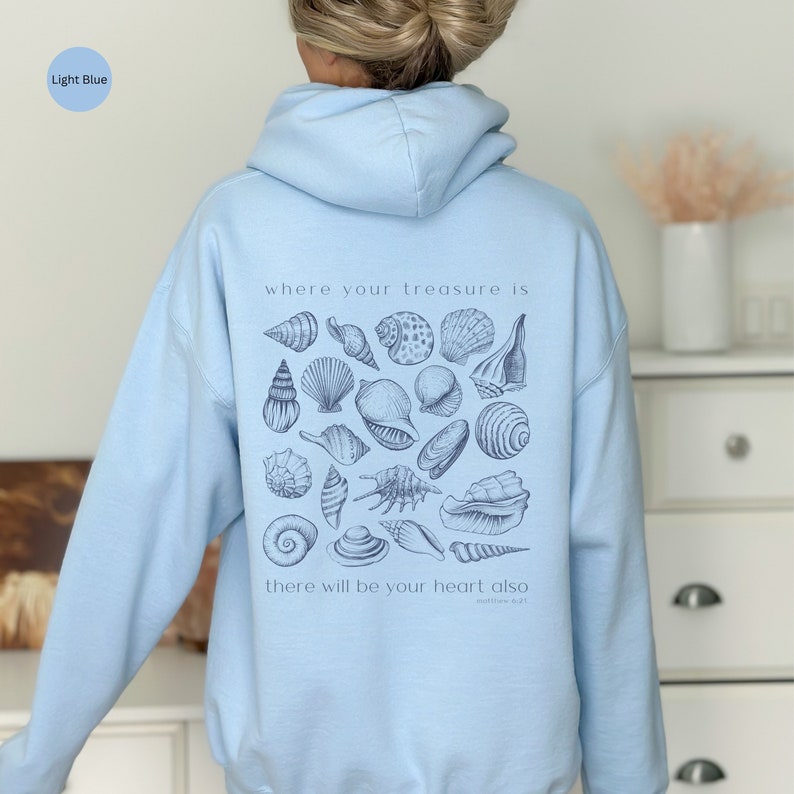 Puede incluir: Sudadera con capucha azul claro con un gr&aacute;fico de conchas marinas y el texto "where your treasure is there will be your heart also Matthew 6:21"