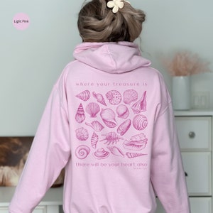 Puede incluir: Sudadera rosa claro con un gr&aacute;fico de conchas marinas y el texto "where your treasure is there will be your heart also Matthew 6:21".