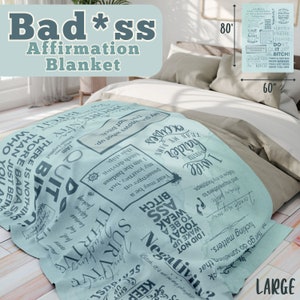 May include: A light blue throw blanket with a large print of motivational text in a dark blue color. The text includes phrases like "I am a badass", "Keep shit up", "Thrive", and "Don't quit, bitch!" The blanket is 60 inches by 80 inches.
