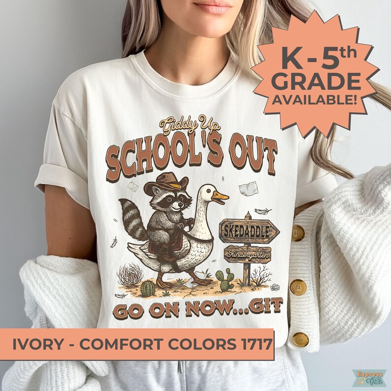 May include: Ivory-colored t-shirt with a graphic featuring a raccoon riding a goose, text that reads "School's Out", and a sign that says "Skedaddle". The shirt also has the text "K-5th Grade Available!" and "Go on now...Git".