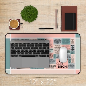 May include: A pink and blue desk mat with a motivational quote design. The mat features a variety of inspirational quotes and phrases, including "Quit Bitch!" and "I am my own damn legend." The mat is 12 inches by 22 inches.