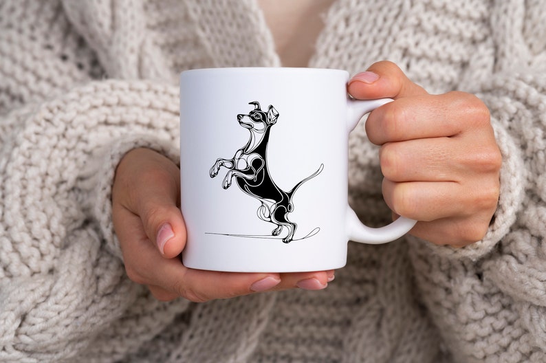 May include: White ceramic mug with a black and white line drawing of a dog standing on its hind legs. The dog has a long tail and is looking to the left.