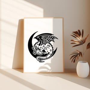 Puede incluir: Un estampado enmarcado con un dise&ntilde;o de drag&oacute;n en blanco y negro. El drag&oacute;n est&aacute; acurrucado dentro de una luna creciente. El drag&oacute;n tiene alas y escamas detalladas. La obra de arte se muestra en un marco de madera de color claro.