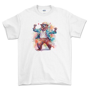 May include: White t-shirt featuring a watercolour illustration of a bear wearing a hat and a plaid shirt, dancing with its arms raised.