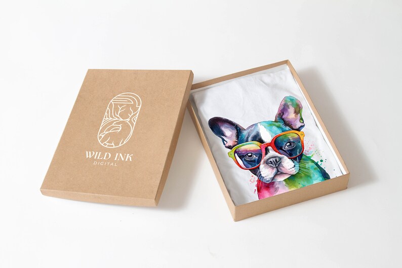 May include: A white t-shirt with a colorful watercolor illustration of a French bulldog wearing sunglasses. The t-shirt is packaged in a brown cardboard box with the logo "WILD INK DIGITAL" printed on the box.