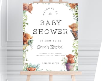 May include: A baby shower welcome sign on an easel. The sign reads "WELCOME TO BABY SHOWER OF MOM-TO-BE Sarah Kitchel" with the date and hashtag. The design includes watercolor illustrations of Highland cows and greenery.