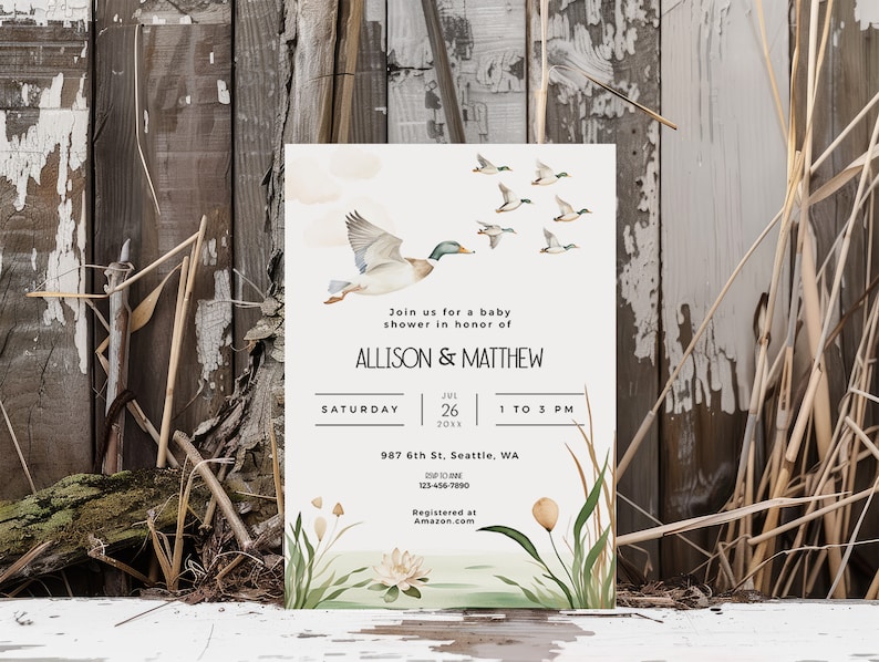 May include: A white baby shower invitation with a watercolor illustration of ducks flying over a pond with cattails and a white water lily. The text reads "Join us for a baby shower in honor of Allison & Matthew, Saturday, June 26, 20XX, 1 to 3 PM, 987 6th St, Seattle, WA, 123-456-7850, Registered at Amazon.com".