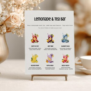 May include: A white rectangular sign titled Lemonade & Tea Bar with instructions and six drink illustrations labeled Cherry on Top, Berry Twist, Blueberry Bliss, Vacation Mode, Purple Reign, and Razzle Dazzle, each listing ingredients below.