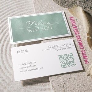 Op de afbeelding: Twee visitekaartjes met een minimalistisch ontwerp. De bovenste kaart heeft een saliegroene aquarel achtergrond met de naam "Melissa Watson" in witte letters. De onderste kaart bevat contactgegevens, social media iconen en een QR-code.