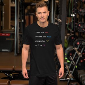May include: Black t-shirt with the text "roses are red, violets are blue, unexpected '{' on line 32" in white, red, blue, and green font. The shirt is worn by a person in a gym setting.