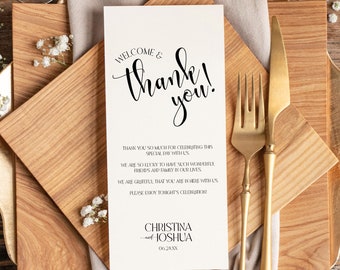 May include: A white welcome and thank you sign with black calligraphy. The sign is on a wooden table with a beige napkin, gold silverware, and two glasses of wine. The text on the sign reads "Welcome & thank you!"  "Thank you so much for celebrating this special day with us."  "We are so lucky to have such wonderful friends and family in our lives."  "We are grateful that you are here with us. Please enjoy tonight's celebration."  "Christina & Joshua"  "06.24.XX"
