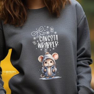 Puede incluir: Una sudadera gris oscuro con un gráfico blanco de un ratón con un sombrero y una chaqueta. El texto "Gangsta Wrapper" está por encima del ratón.