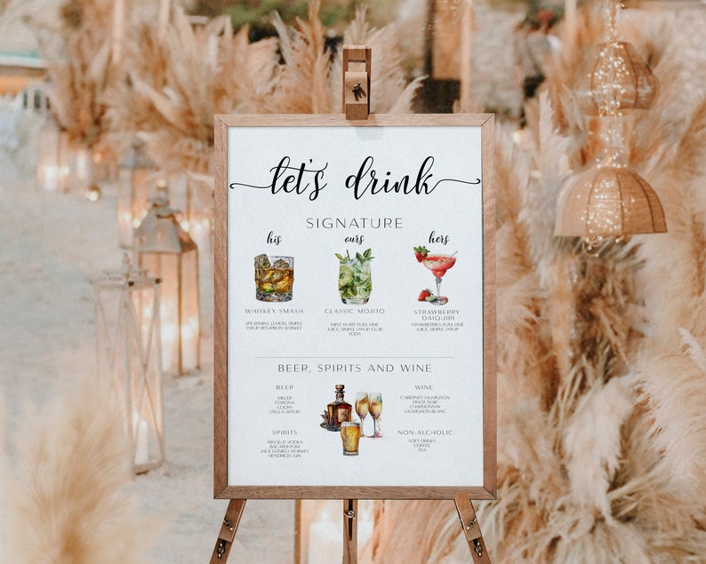 May include: A white sign with the text "let's drink" in black cursive font. The sign lists signature drinks for a wedding, including "Whiskey Smash", "Classic Mojito", and "Strawberry Daiquiri". The sign also lists beer, spirits, and wine options.
