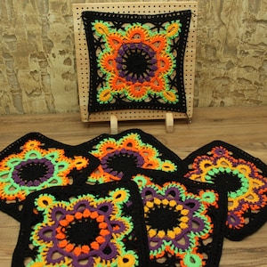 Peut inclure: Six carrés en crochet de couleur noire, orange, verte et violette. Les carrés ont un motif circulaire au centre et sont disposés en quinconce.