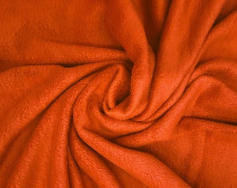 May include: A close-up of a bright orange fabric, folded and twisted into a spiral shape. The fabric has a soft, fuzzy texture.